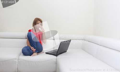 Image of Woman Drinking Water Near a Laptop