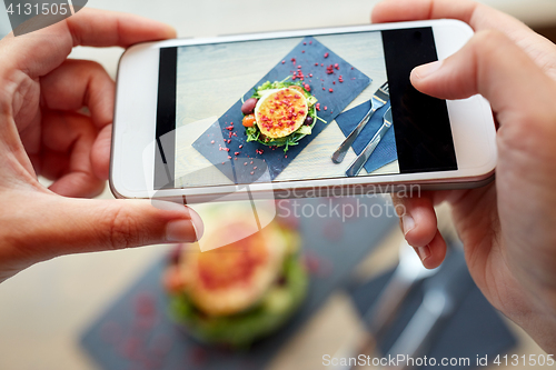 Image of hands with smartphone photographing food