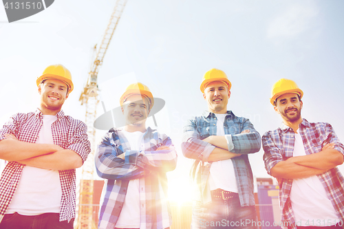 Image of group of smiling builders in hardhats outdoors