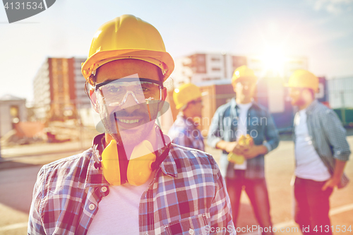 Image of smiling builder with hardhat and headphones