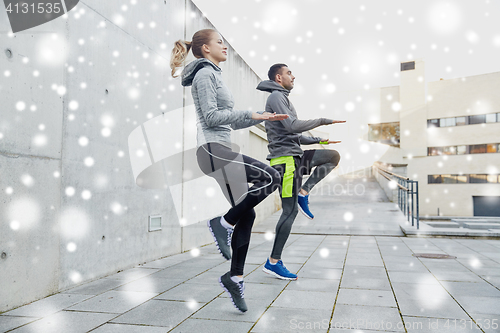 Image of happy man and woman jumping outdoors