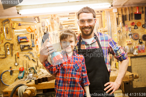 Image of father and son with drill working at workshop