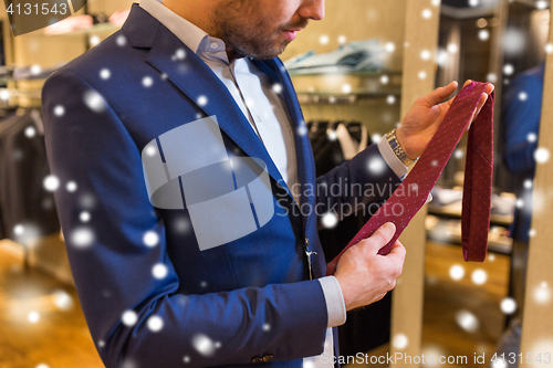 Image of close up of man trying tie on at clothing store