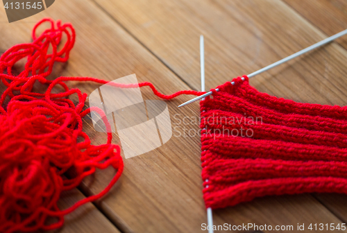 Image of hand-knitted item with knitting needles on wood