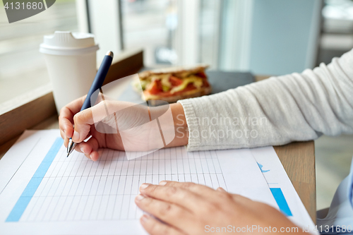Image of woman with paper form having lunch at cafe
