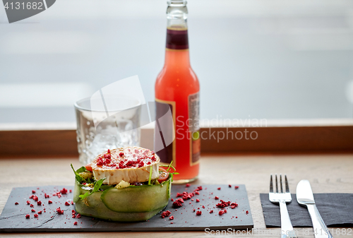 Image of salad, bottle of drink, glass and cutlery on table