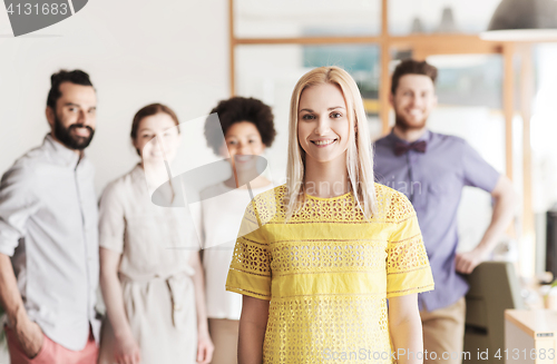 Image of happy young woman over creative team in office