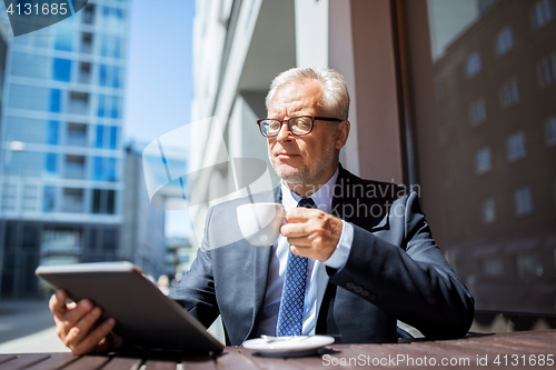 Image of senior businessman with tablet pc drinking coffee