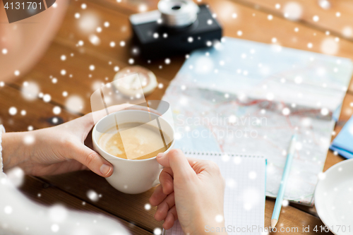 Image of close up of hands with coffee cup and travel stuff