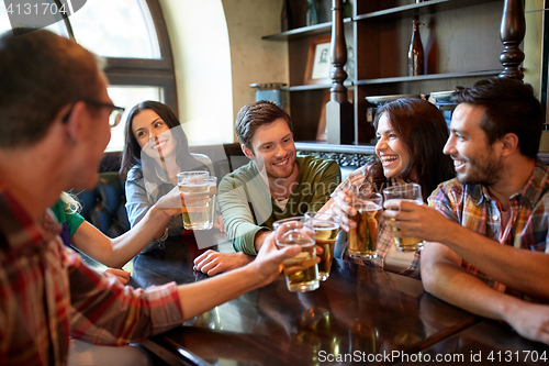 Image of happy friends drinking beer at bar or pub