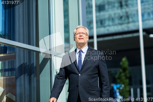 Image of senior businessman walking along city street