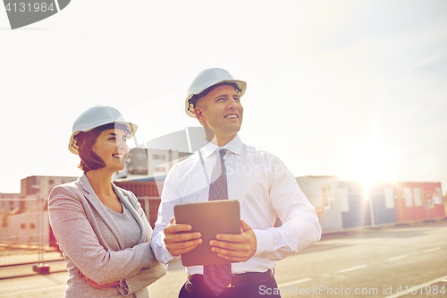 Image of happy builders in hardhats with tablet pc outdoors