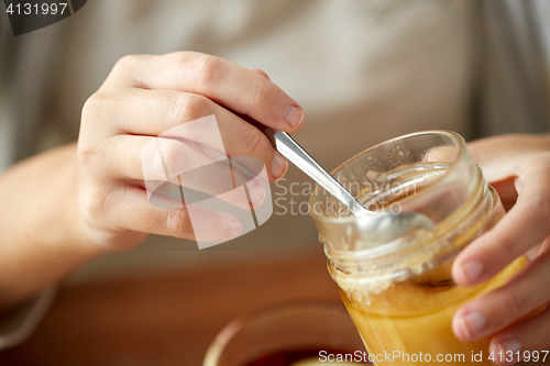 Image of close up of woman hands with honey jar and spoon