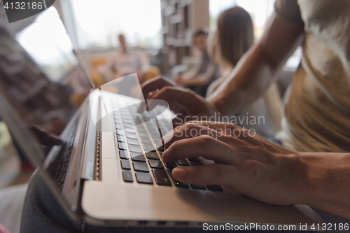 Image of close up of male hands while working on laptop