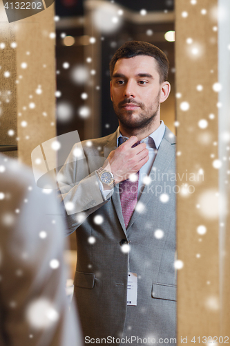 Image of man trying jacket on at mirror in clothing store