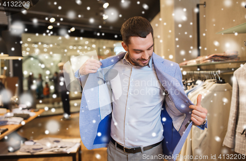 Image of happy young man trying jacket on in clothing store