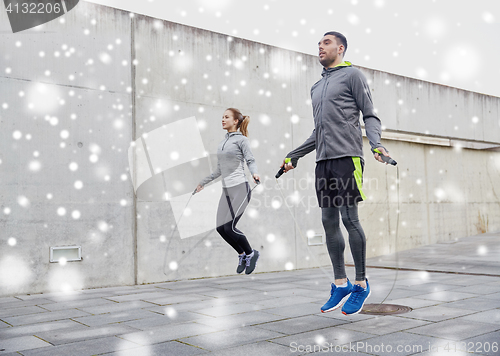 Image of man and woman exercising with jump-rope outdoors