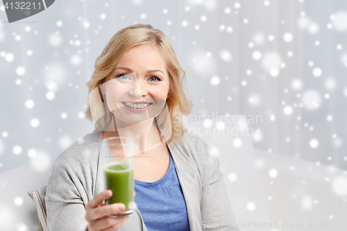 Image of happy woman drinking green juice or shake at home