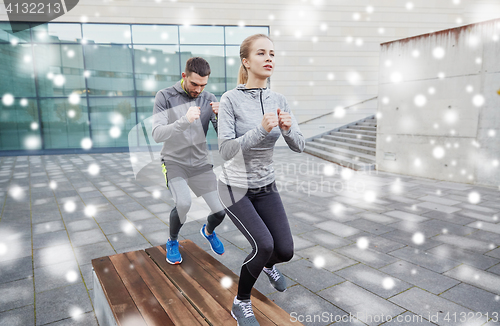 Image of couple of sportsmen making step exercise on bench