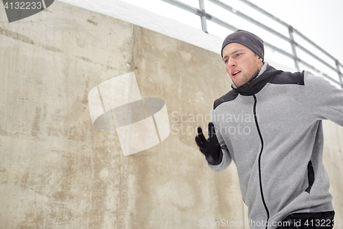 Image of man running along concrete wall in winter