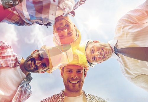 Image of close up of builders wearing  hardhats in circle