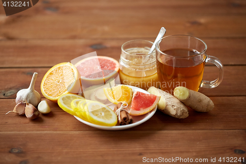 Image of ginger tea with honey, citrus and garlic on wood