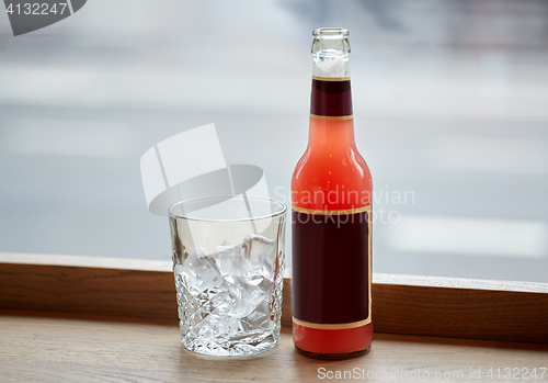 Image of bottle of lemonade and glass with ice on table