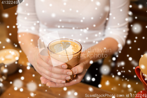 Image of close up of hands with latte art in coffee cup