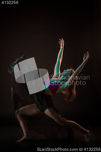 Image of Young beautiful dancer in beige dress dancing on black background