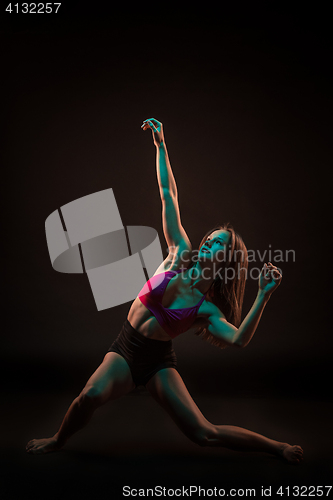 Image of Young beautiful dancer in beige dress dancing on black background