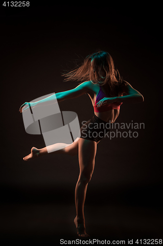 Image of Young beautiful dancer in beige dress dancing on black background