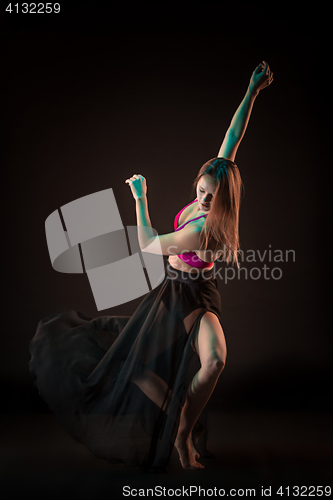 Image of Young beautiful dancer in beige dress dancing on black background