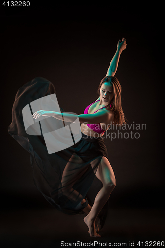 Image of Young beautiful dancer in beige dress dancing on black background