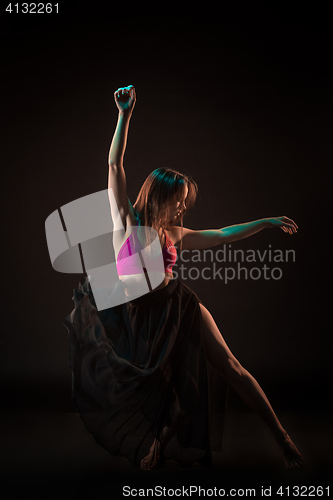 Image of Young beautiful dancer in beige dress dancing on black background