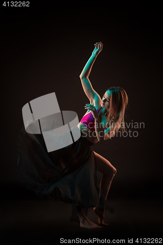 Image of Young beautiful dancer in beige dress dancing on black background