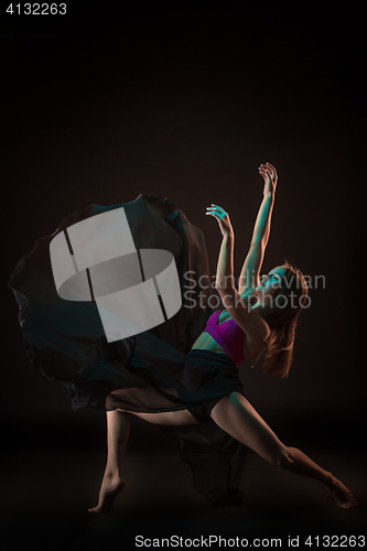 Image of Young beautiful dancer in beige dress dancing on black background