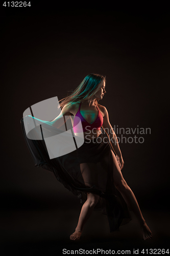 Image of Young beautiful dancer in beige dress dancing on black background