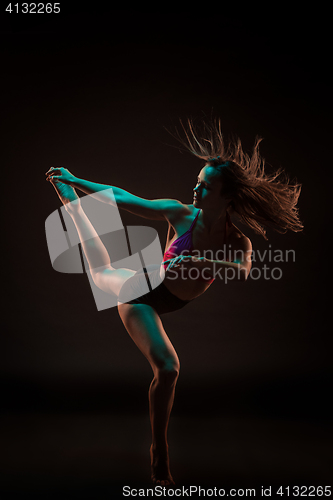 Image of Young beautiful dancer in beige dress dancing on black background