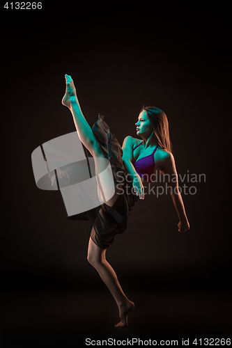 Image of Young beautiful dancer in beige dress dancing on black background