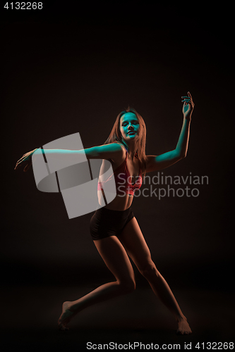 Image of Young beautiful dancer in beige dress dancing on black background