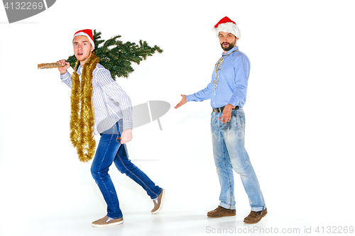 Image of The young man in Santa cap carrying Christmas tree