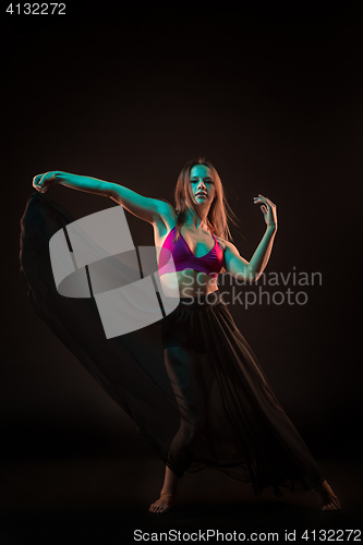 Image of Young beautiful dancer in beige dress dancing on black background