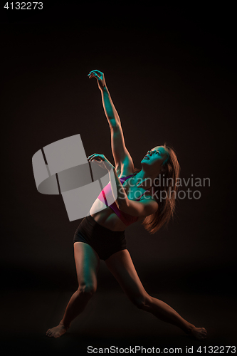 Image of Young beautiful dancer in beige dress dancing on black background