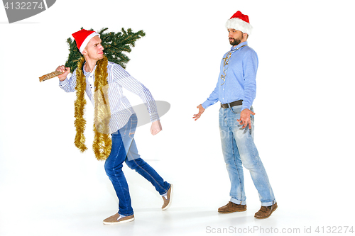 Image of The young man in Santa cap carrying Christmas tree