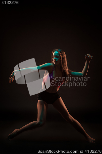 Image of Young beautiful dancer in beige dress dancing on black background