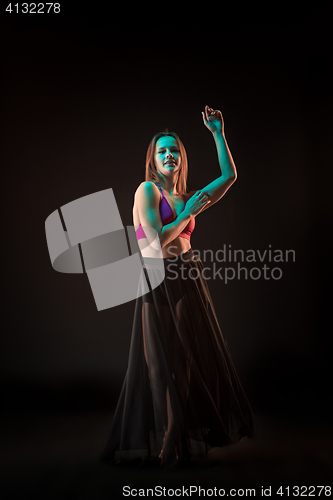 Image of Young beautiful dancer in beige dress dancing on black background