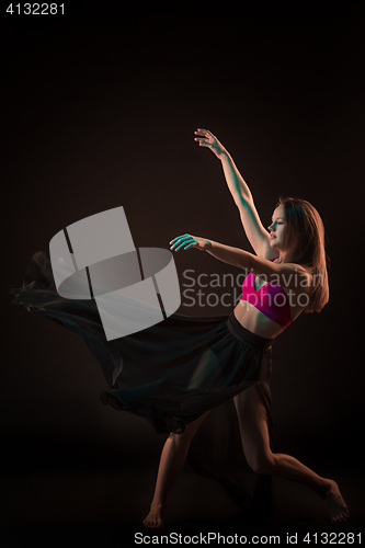 Image of Young beautiful dancer in beige dress dancing on black background