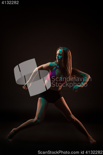 Image of Young beautiful dancer in beige dress dancing on black background