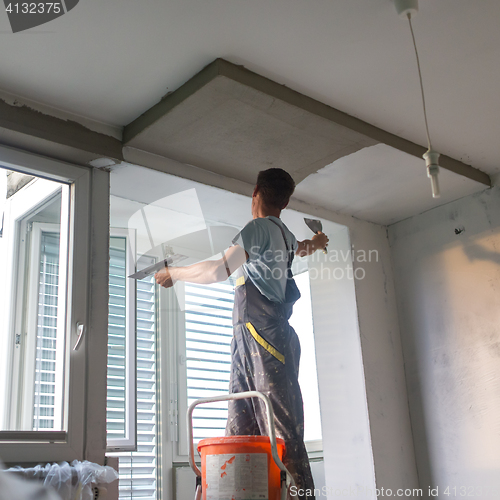 Image of Plasterer renovating indoor walls and ceilings. Construction finishing works.