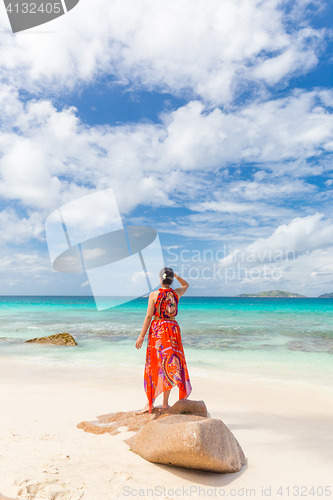 Image of Woman enjoying Anse Patates picture perfect beach on La Digue Island, Seychelles.